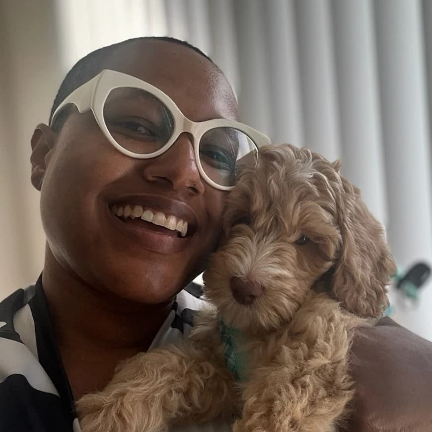 A guest smiling cheek to cheek with an apricot Australian Labradoodle puppy